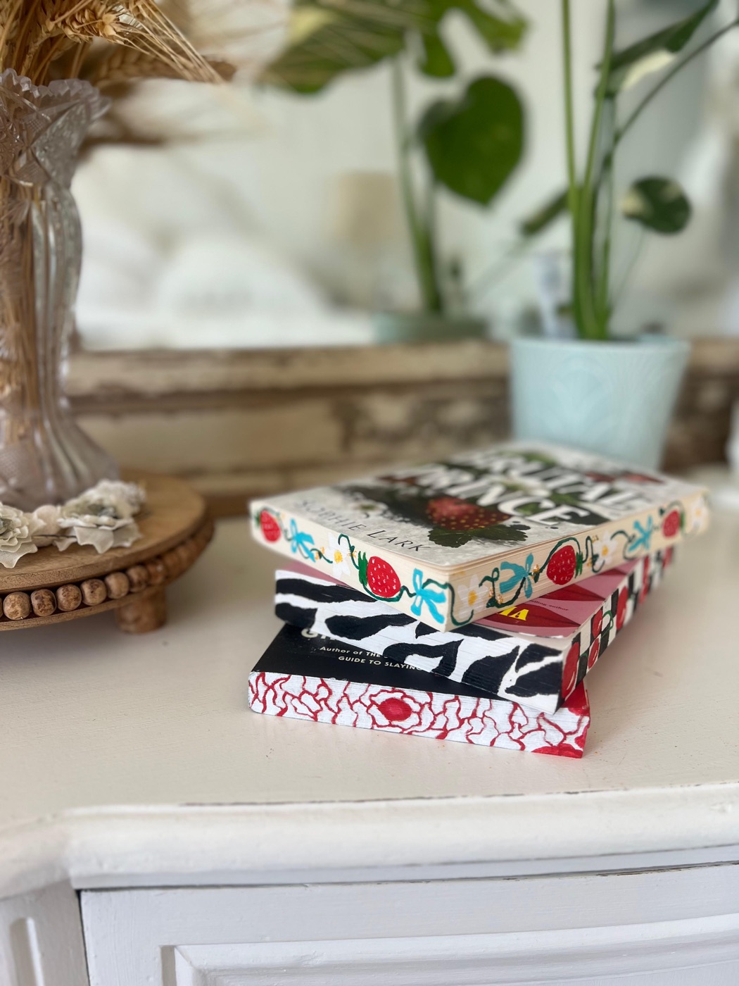 Stacked books with hand-painted strawberries, bows, black-and-white patterns and red flowers on their page edges